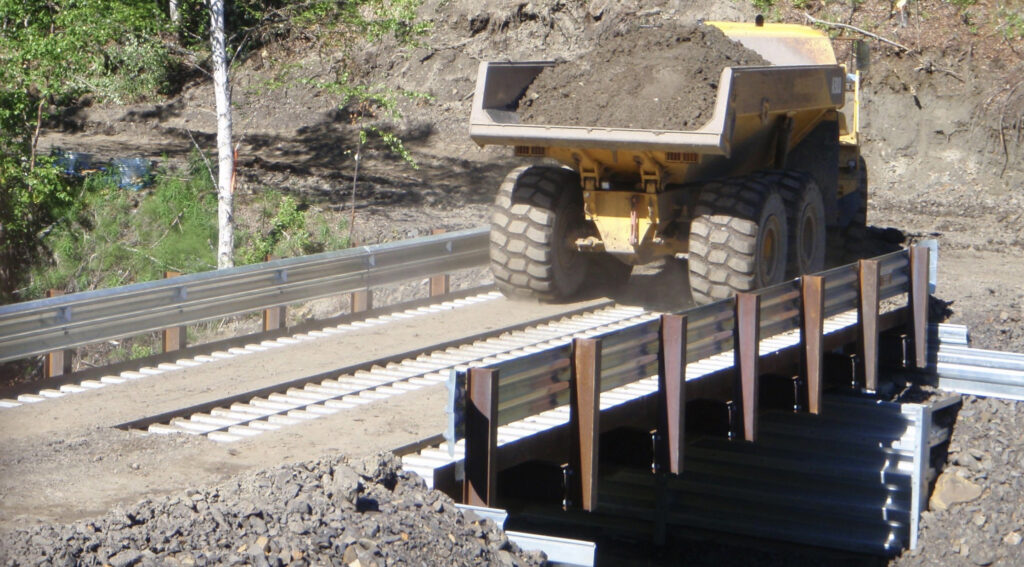 Heavy-duty mining vehicle crossing a steel girder bridge