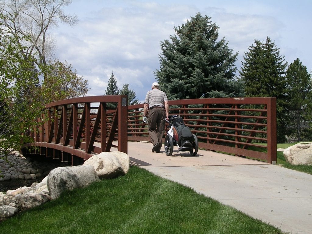 Golfer crossing golf course-bridge with concrete decking