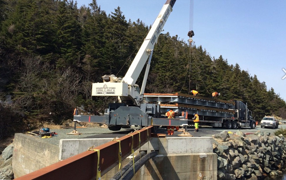 Side view of bridge components crane-lifted off flatbed truck