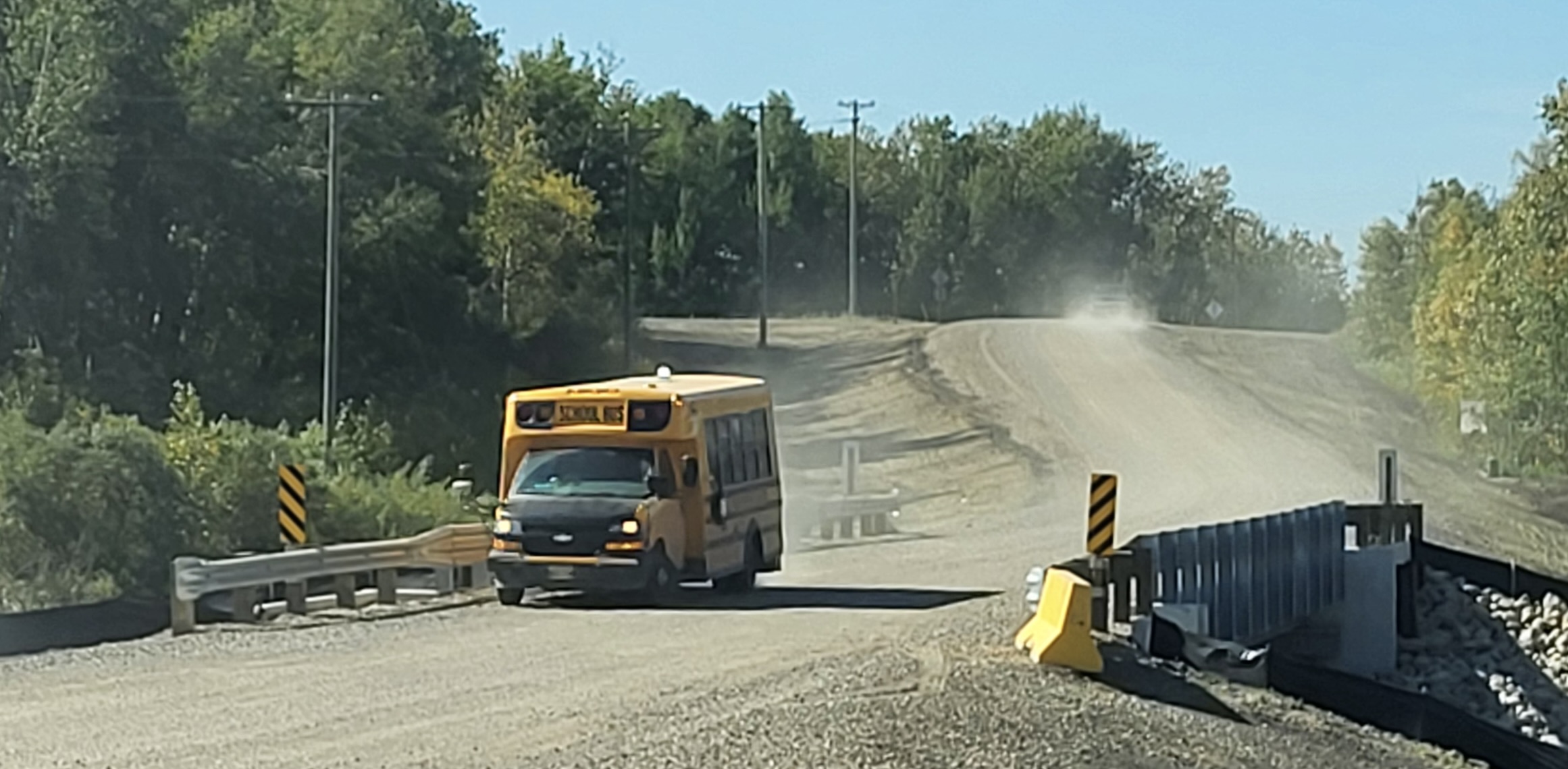 School bus crossing Steel Girder Bridge with gravel deck